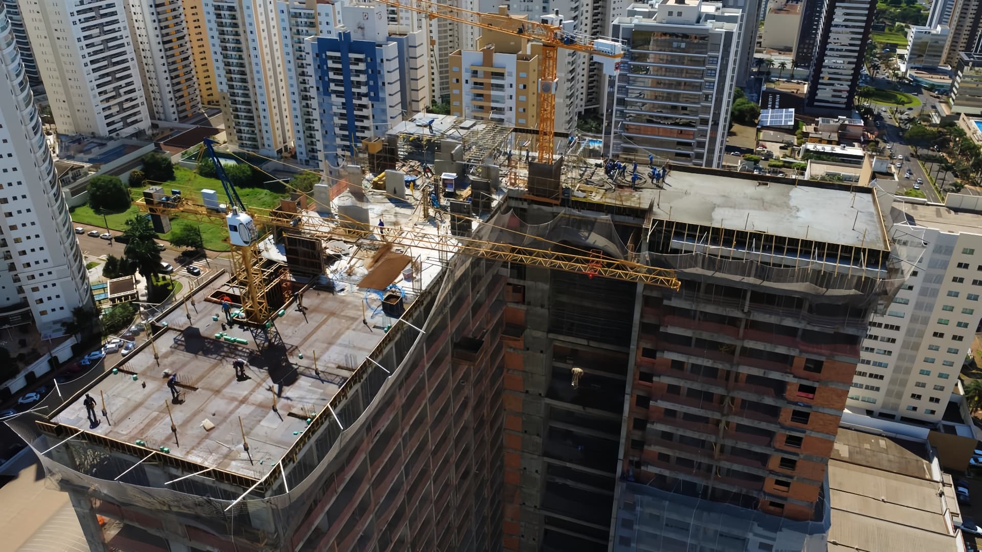 Vista aérea do topo de obra com gruas e trabalhadores na laje